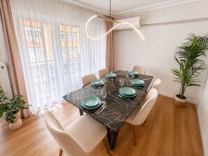 Een eetgedeelte met een marmeren tafel, stoelen en een potplant.