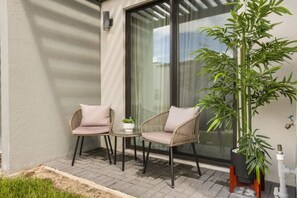 A small outdoor seating area with two wicker chairs and a table, a potted plant, and a sliding glass door. - 3 BD/ 3 BA/ The Hub at Westside Reserve - 3209 ED (Kissimmee)