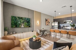 Een moderne woonkamer met een bank, een salontafel en een aan de muur bevestigde televisie.