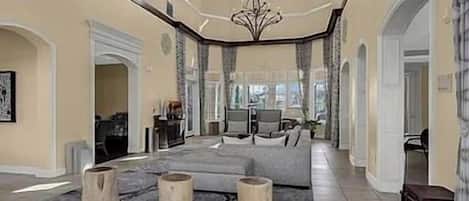 A spacious lobby with a high ceiling, a chandelier, and a seating area with sofas and a coffee table.