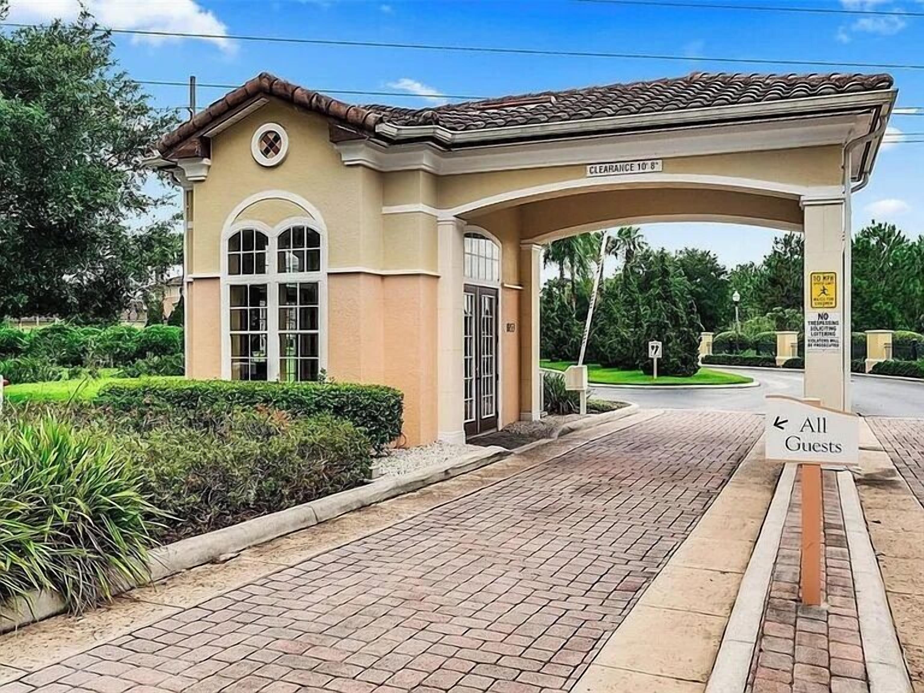 A hotel entrance with a covered waiting area, a sign for 'All Guests', and a clear pathway leading to the entrance.