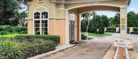 A hotel entrance with a covered waiting area, a sign for 'All Guests', and a clear pathway leading to the entrance.