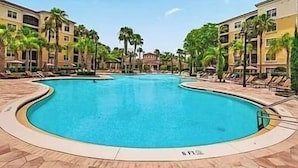 En swimmingpool omgivet af palmer og hotelbygninger.
