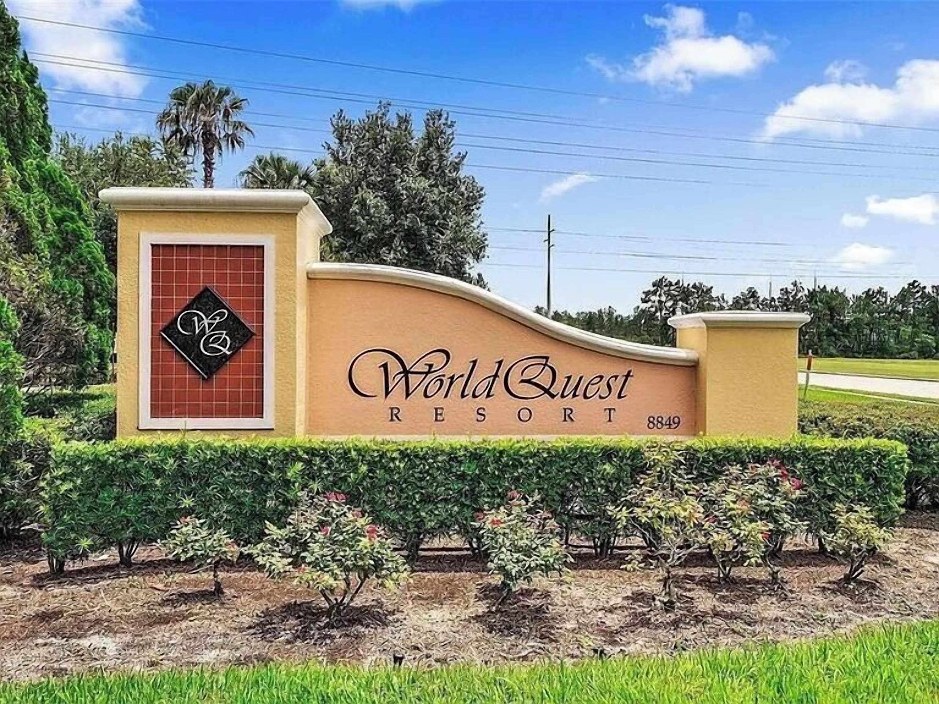 Señalización para World Quest Resort, con vista clara a la entrada y la vegetación circundante.