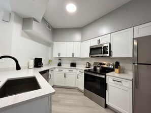 A modern kitchen with white cabinetry, stainless steel appliances, and a black countertop. - 3 BD/ 2 BA/ WorldQuest Resort (4-102 WB) (Orlando)