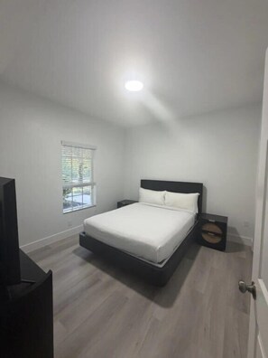 Een slaapkamer met een bed, een raam en een deur.