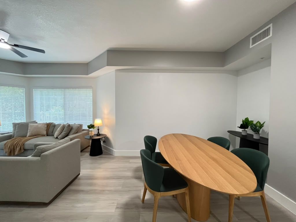 Una sala moderna con un sofá, una mesa de comedor con sillas y un ventilador de techo.
