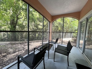 A covered patio with a table and chairs, large windows, and a view of a wooded area. - 3 BD/ 2 BA/ WorldQuest Resort (4-102 WB) (Orlando)