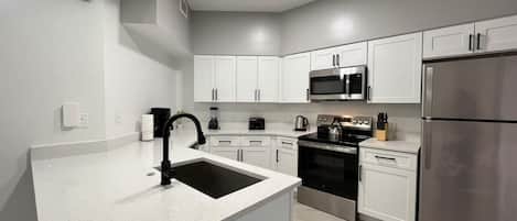 A modern kitchen with white cabinetry, stainless steel appliances, and a granite countertop.