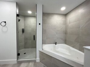 Ein modernes Badezimmer mit einer gläsernen Duschkabine, einer freistehenden Badewanne und gefliesten Wänden.