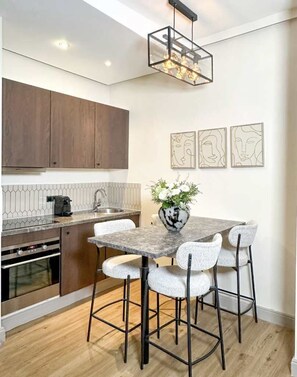 A modern kitchen with a dining area, featuring a marble table, bar stools, and a pendant light. - Superb Appartment close to Marais by Melvane 4P (Paris)