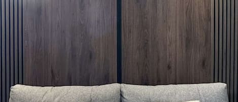 Un sofá con dos almohadas frente a una pared de listones de madera y dos luces instaladas en la pared.
