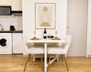 A dining table with two chairs, a framed artwork above, and a kitchen in the background. - Saint Germain Deluxe Studio by Melvane (Paris)