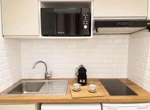 A kitchenette with a microwave, coffee maker, sink, and induction cooktop. - Saint Germain Deluxe Studio by Melvane (Paris)