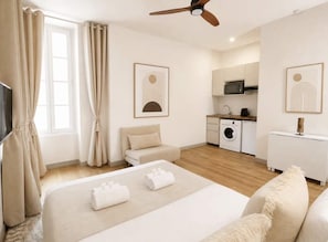 A modern hotel room with a bed, a sofa, a ceiling fan, a washing machine, and a kitchenette. - Saint Germain Deluxe Studio by Melvane (Paris)