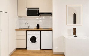 A compact kitchen with a washing machine, a microwave, and a dishwasher. - Saint Germain Deluxe Studio by Melvane (Paris)