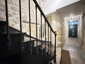 A staircase with stone walls and a dark wooden handrail. - Saint Germain Deluxe Studio by Melvane (Paris)