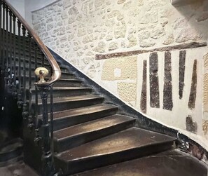 A staircase with a black handrail and a stone wall with a textured pattern. - Saint Germain Deluxe Studio by Melvane (Paris)