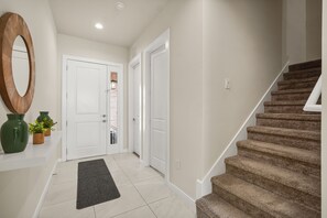 Ein Flur mit Teppich und einer Wendeltreppe, weißen Türen und einem Spiegel an der Wand.