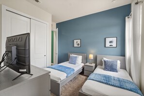Ein Hotelzimmer mit zwei Betten, einem Schreibtisch, einem Fernseher und Bildern an den Wänden.