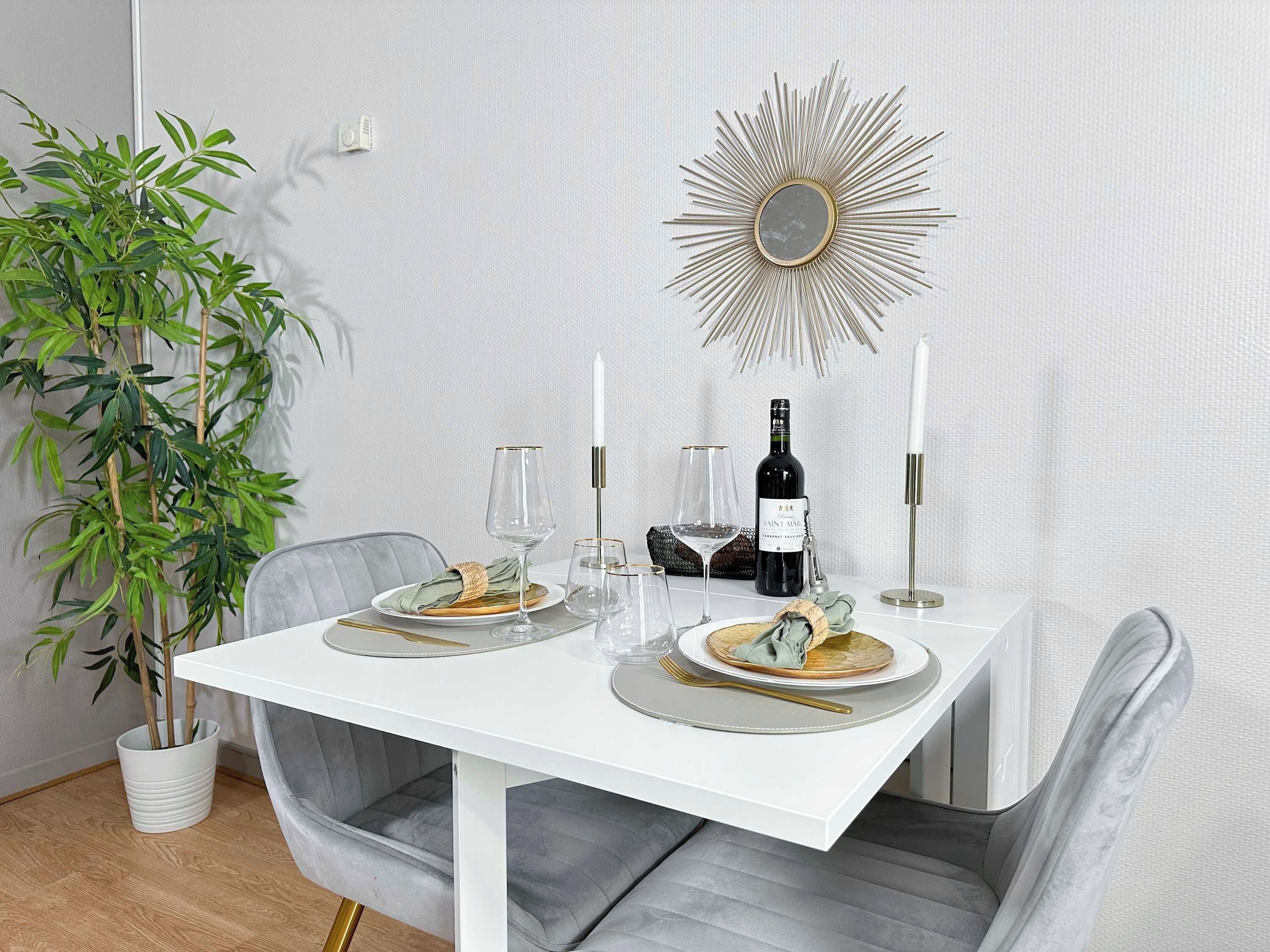 A dining table set with plates, glasses, a bottle, and candles.