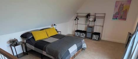 A bedroom with a bed, a nightstand, a lamp, and a wall-mounted shelf.