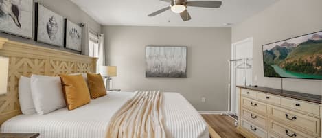 Un dormitorio con cama, ventilador de techo, cómoda y televisor.