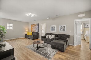 A modern living room with a grey sofa set, a coffee table, and a large abstract painting on the wall. - 6 BD/ 5.5 BA/ Solterra Resort (6043 BO) (Davenport)