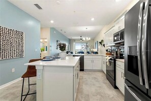 A modern kitchen with white cabinetry, a black refrigerator, and a central island with seating. - 2 BD/ 2 BA/ Storey Lake (3141-404 PC) (Kissimmee)