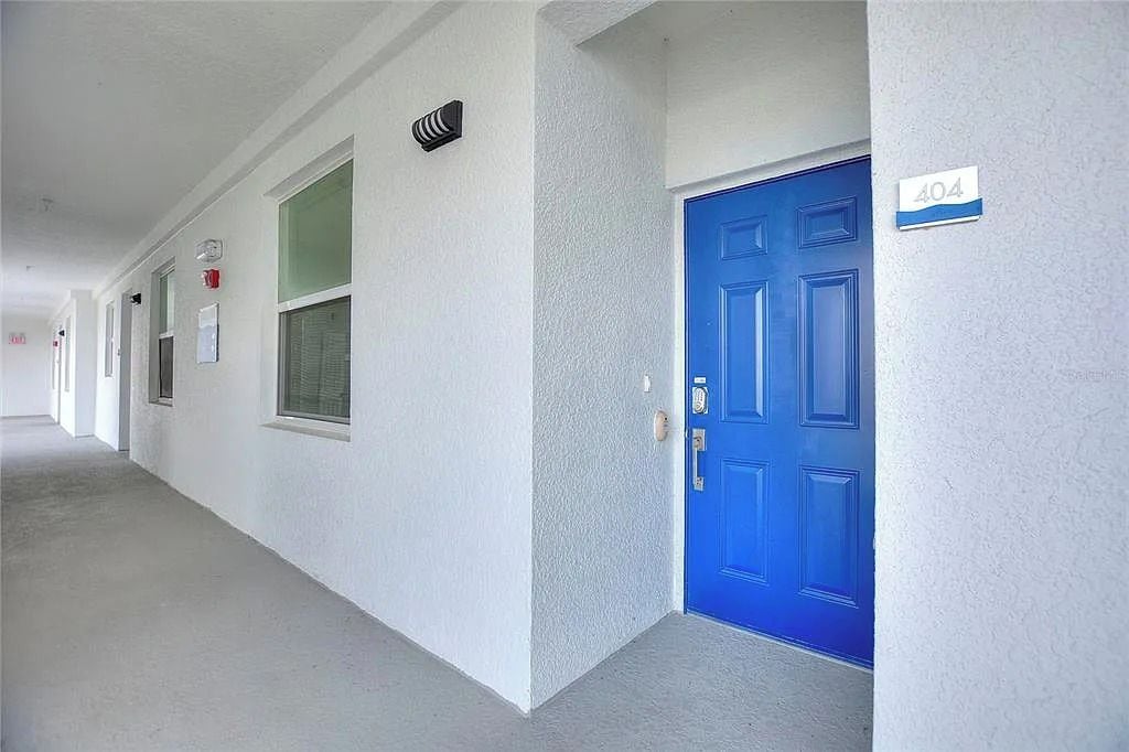 A hallway with a blue door marked '404' and a fire alarm on the wall.