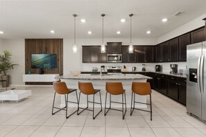 A modern kitchen with a central island, bar stools, stainless steel appliances, and pendant lighting. - 10 BD/ 8 BA/ Windsor Island Resort (4321 LA) (Davenport)