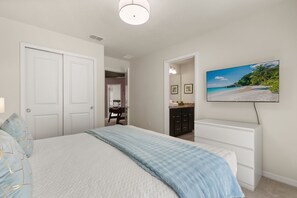 A bedroom with a bed, a dresser, a television, and a door leading to another room. - 10 BD/ 8 BA/ Windsor Island Resort (4321 LA) (Davenport)