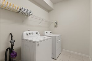 A laundry room with two front-loading washers and dryers, a ceiling-mounted drying rack, and a vacuum cleaner. - 10 BD/ 8 BA/ Windsor Island Resort (4321 LA) (Davenport)