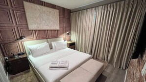 A hotel room with a large bed, a bedside table with a lamp, and a curtain covering the window. - 3 BD/ 3.5 BA/ Magic Village by Pininfarina (5591 PW) (Kissimmee)
