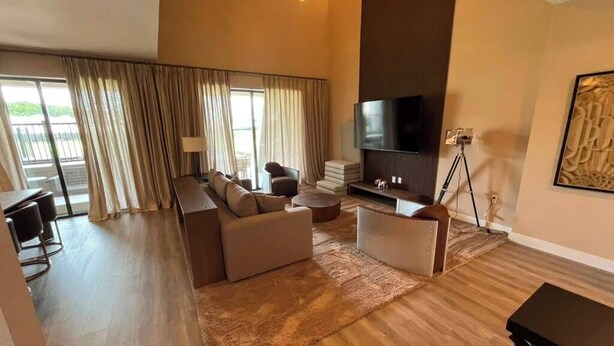 A modern living room with a sofa set, a flat-screen TV, and a dining table. - 3 BD/ 3.5 BA/ Magic Village by Pininfarina (5591 PW) (Kissimmee)