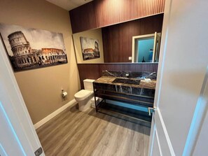 Een badkamer met een marmeren wastafel, houten lambrisering en een toilet.