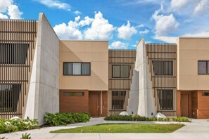 A modern building with a symmetrical facade, large windows, and a central courtyard with greenery. - Brand New! 3 Bd/3.5 Ba/ Magic Village by Pininfarina - 5591 PW (Kissimmee)