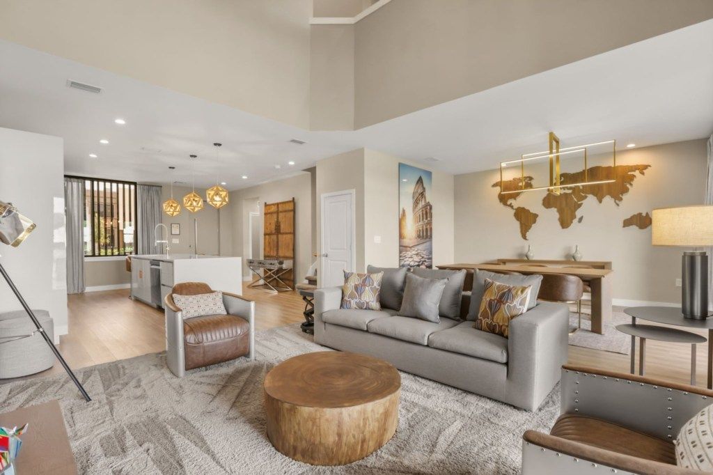 A modern living room with a grey sofa, a round wooden coffee table, and a world map on the wall.