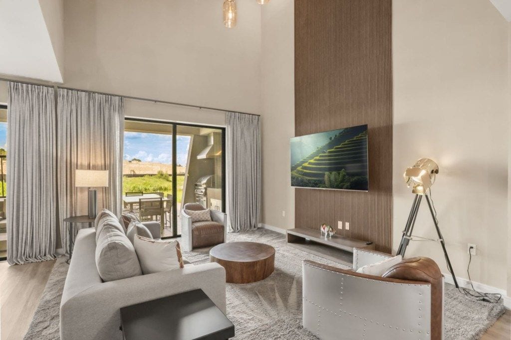 Un salon moderne avec un canapé, une table basse et un téléviseur à écran plat fixé au mur.