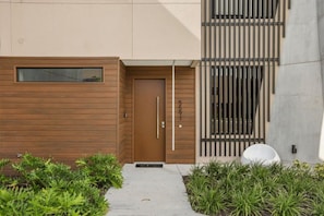 A modern building with a wooden door, a small window, and a concrete wall with vertical bars. - Brand New! 3 Bd/3.5 Ba/ Magic Village by Pininfarina - 5591 PW (Kissimmee)