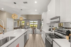 A modern kitchen with a central island, built-in appliances, and pendant lighting. - Brand New! 3 Bd/3.5 Ba/ Magic Village by Pininfarina - 5591 PW (Kissimmee)