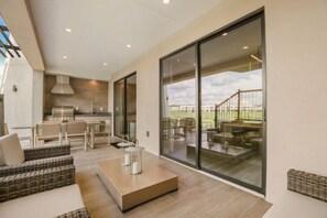 A modern kitchen with a dining area, large sliding glass doors to an outdoor patio, and a view of a staircase. - Brand New! 3 Bd/3.5 Ba/ Magic Village by Pininfarina - 5591 PW (Kissimmee)