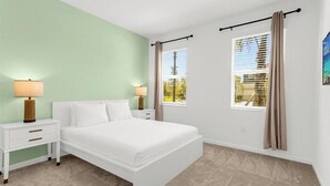 A bedroom with a bed, two bedside tables, a window with curtains, and a wall with a light green color. - 8 BD/ 5 BA/ Bella Vida (4489 MD) (Kissimmee)