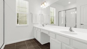 A bathroom with a white vanity, a large mirror, and a window with blinds. - 8 BD/ 5 BA/ Bella Vida (4489 MD) (Kissimmee)