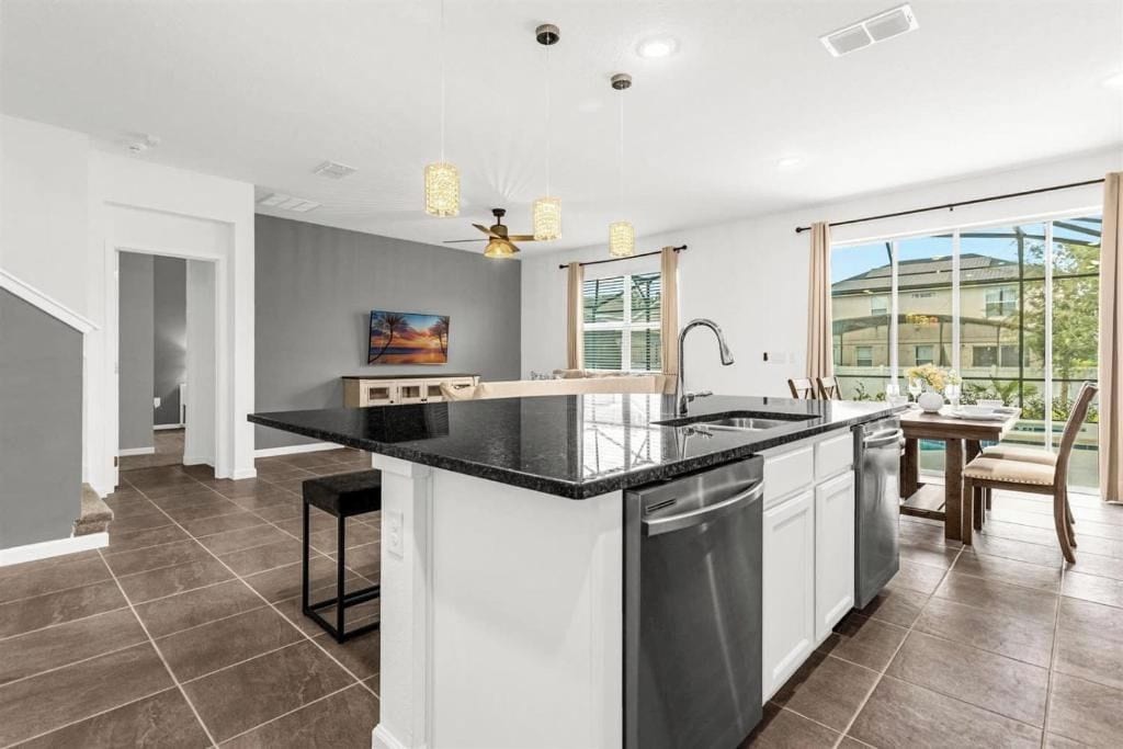 A modern kitchen with a central island, a dining area with a table and chairs, and a view of the outdoors through large windows.