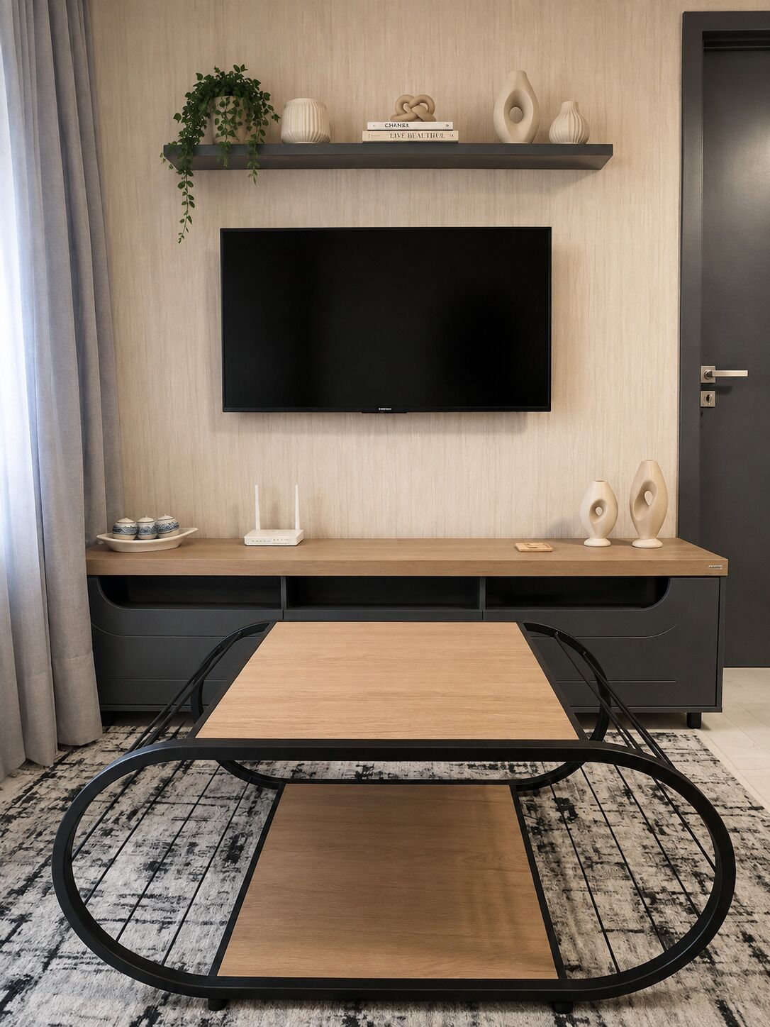 A modern living room with a flat-screen TV mounted on the wall, a wooden coffee table, and a black-framed chair.