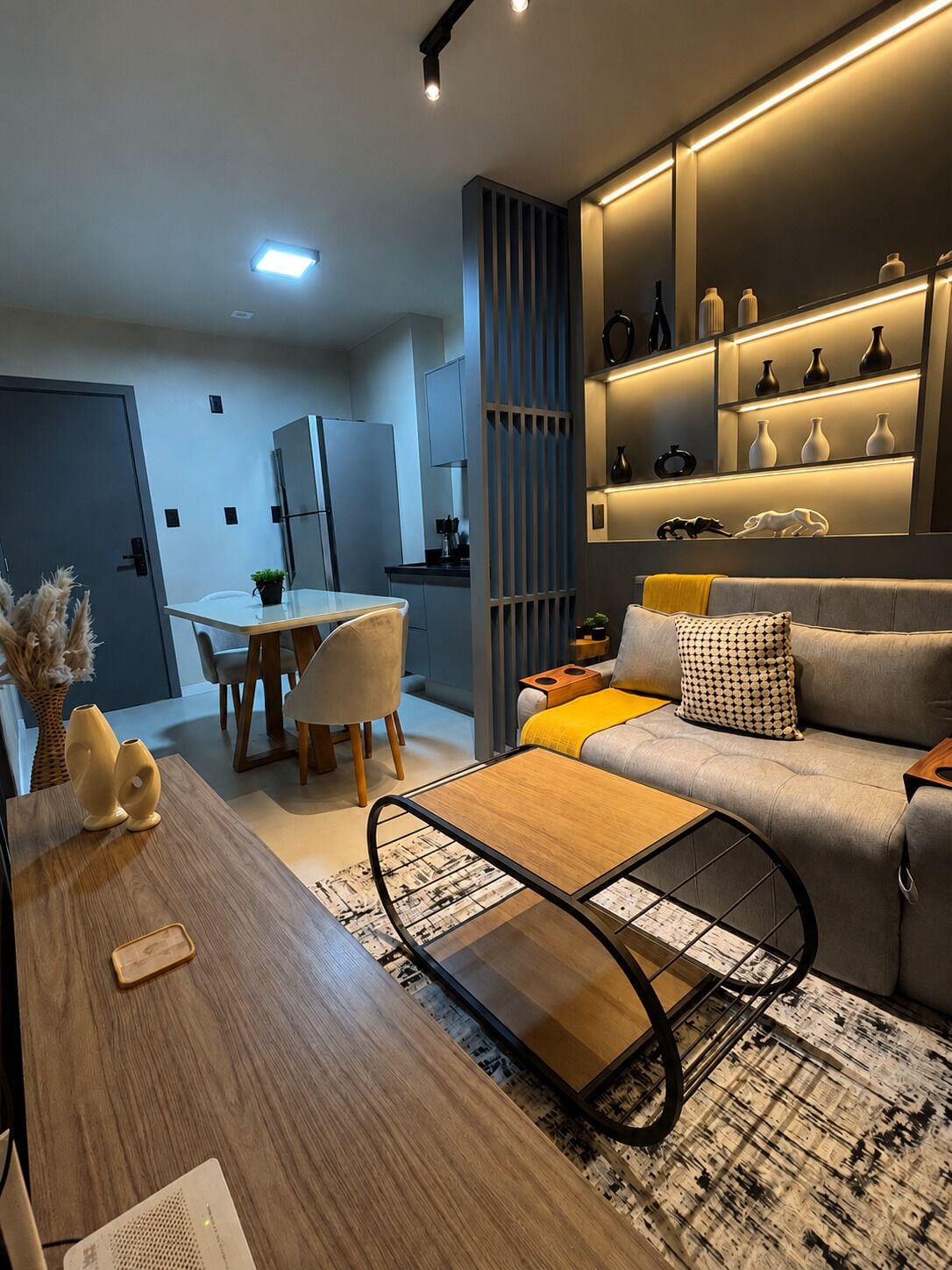 A modern living room with a sofa, coffee table, and a dining area with chairs and a table.