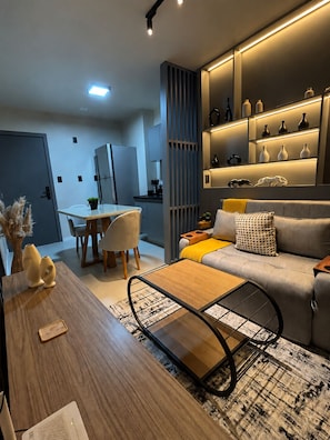 Een moderne woonkamer met een bank, salontafel en een eethoek met stoelen en een tafel.