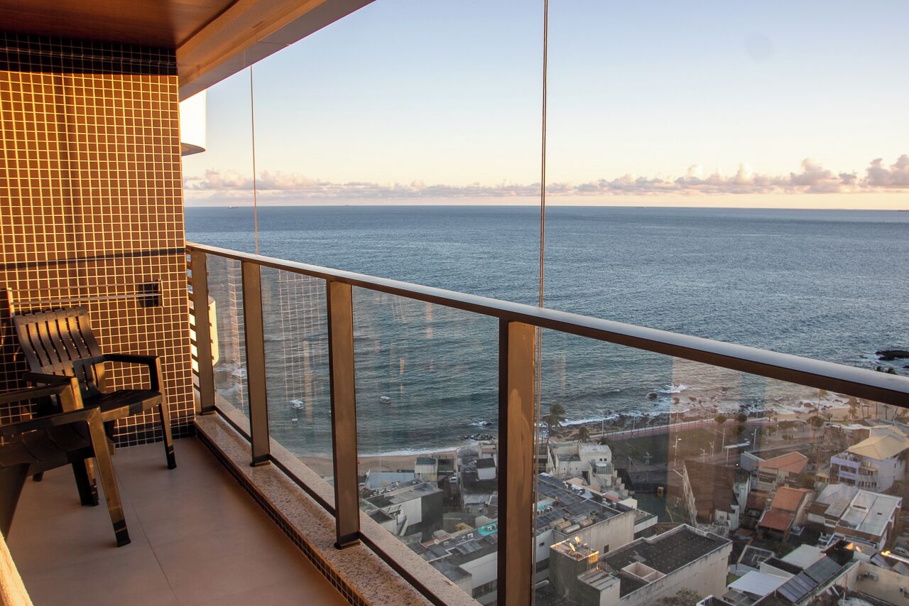 A balcony with a view of the sea and a cityscape.