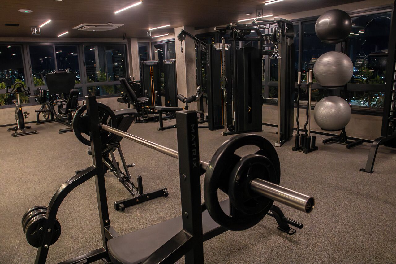 A gym with various exercise equipment, including a squat rack and weight plates.